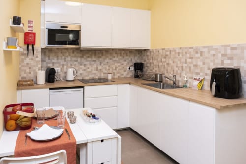 Modern white kitchen with wooden counters, beige tile backsplash, dining area, and appliances in RH Charming Apartment Braga