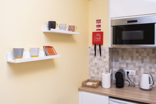 Modern kitchen corner at RH Charming Apartments Braga with white shelves, stainless steel microwave, kettle, and decorative