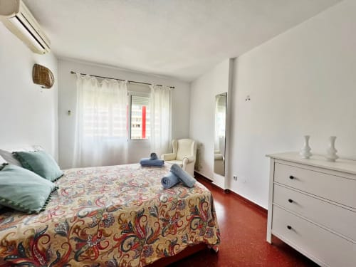 Dormitorio de apartamento frente al mar en Fuengirola con vistas al mar, muebles blancos y colcha estampada