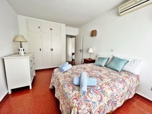 Dormitorio de apartamento frente al mar en Fuengirola con colcha colorida, armario blanco y vistas al mar