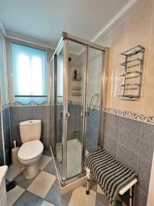 Baño moderno en apartamento frente al mar en Fuengirola con ducha, inodoro, toallero calefactable y vistas al mar