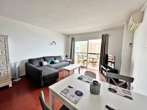Apartamento en primera línea de playa en Fuengirola con sofá gris, comedor, balcón con vistas al mar, aire acondicionado y amenidades modernas