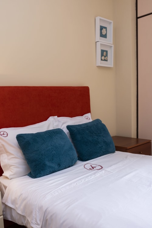 Bedroom in RH Charming Apartments, Braga with red headboard, white bedding, teal cushions and wall art