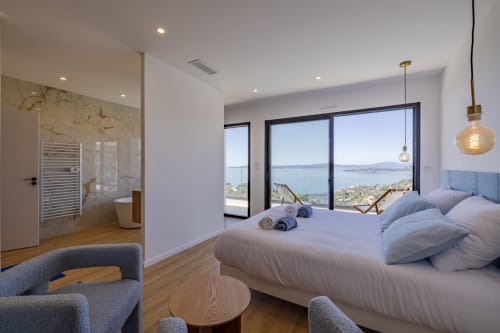 Chambre luxueuse à Villa Prestige Azur Antilles avec vue sur mer, mobilier moderne, salle de bain privée et terrasse panoramique