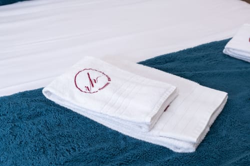Folded white towels with embroidered logo on teal towel at RH Charming Apartments, Braga