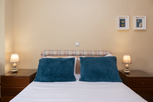 Cozy bedroom at RH Charming Apartment São Victor in Braga with white bed, teal pillows, striped headboard, wooden