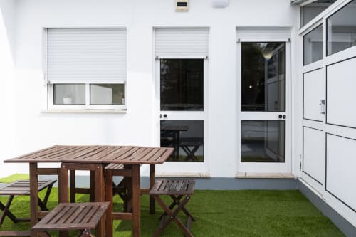 Modern apartment terrace at RH Charming Apartments Braga with wooden furniture, artificial turf, and white building facade