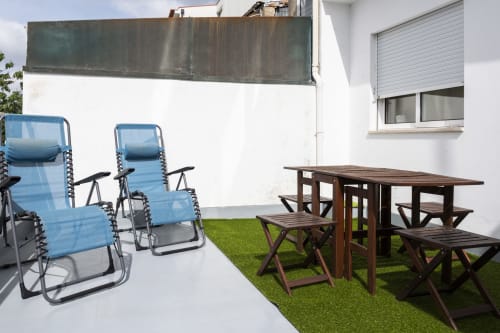 Private terrace at RH Charming Apartments Braga with blue lounge chairs and wooden dining table on artificial grass