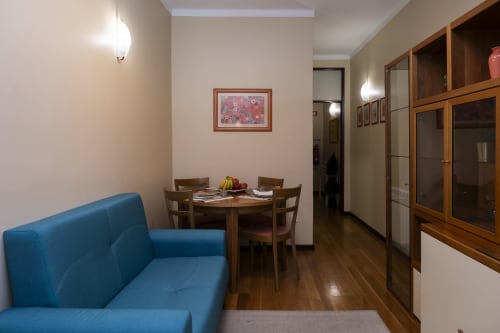 Modern apartment living area with blue sofa, wooden dining table, and built-in cabinetry at RH Charming Apartments in Braga