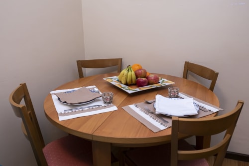 Dining area at RH Charming Apartment São Victor in Braga with wooden table, chairs, fresh fruit platter, and place settings