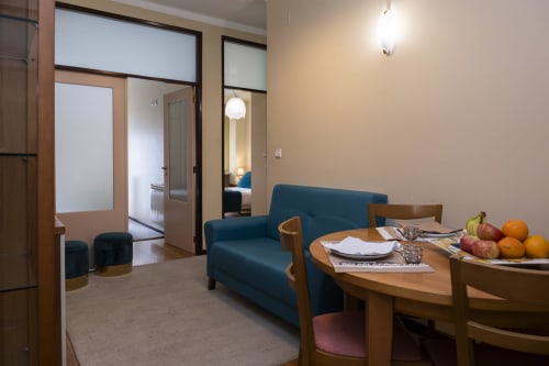RH Charming Apartment São Victor in Braga: modern living room with blue sofa, wooden dining table, fresh fruit, and open