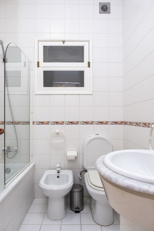 Clean bathroom in RH Charming Apartments Braga with white tiles, toilet, bidet, sink, and shower area