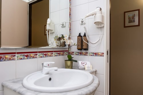 Modern bathroom with round white sink, decorative tile border, and shower in RH Charming Apartments, Braga