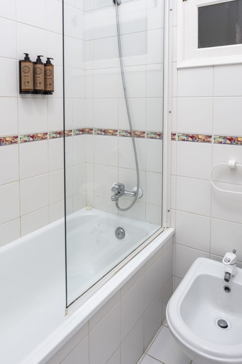 Modern bathroom shower with white tiles and decorative border trim at RH Charming Apartments in Braga, Portugal