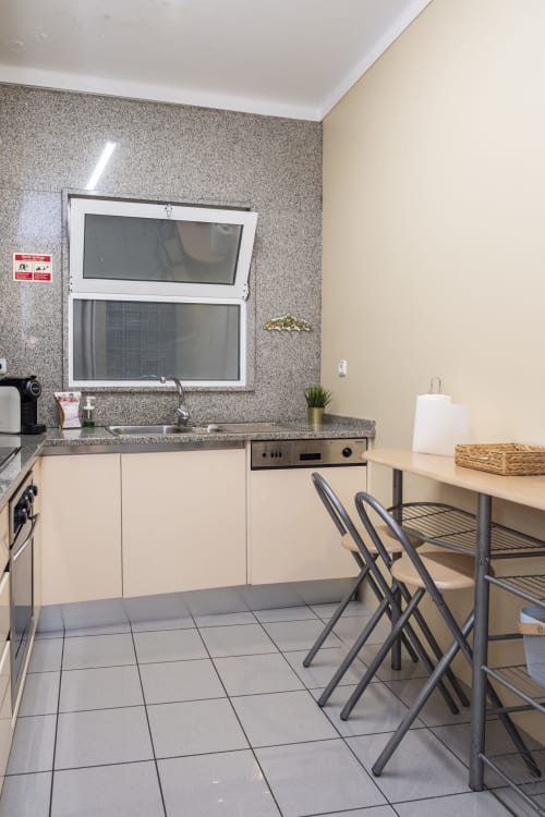 Modern kitchen at RH Charming Apartments Braga with cream cabinets, granite countertop, window, and dining area
