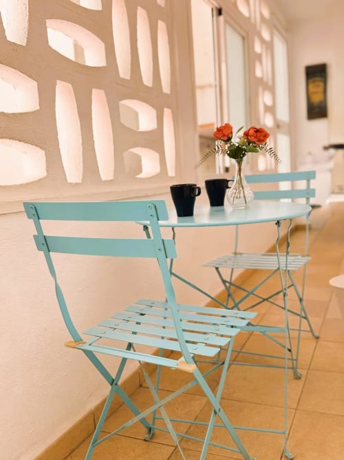 Mobiliario exterior color turquesa en balcón del apartamento de Fuengirola con flores frescas y tazas de café