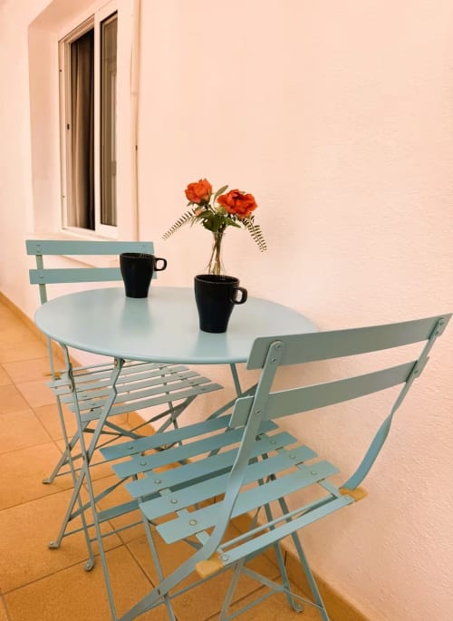 Mesa de bistró turquesa con sillas en terraza con flores naranjas, zona de estar en balcón de apartamento en Fuengirola