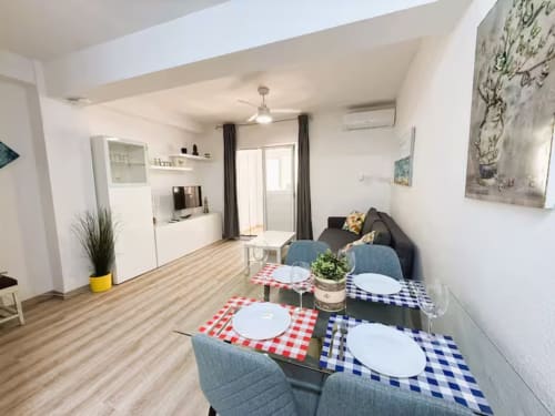 Moderno apartamento en Fuengirola con zona de comedor, cocina equipada, salón con sofá y muebles blancos