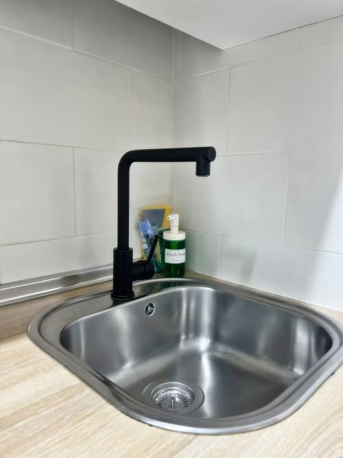 Fregadero moderno con grifo negro y azulejos tipo metro blancos en apartamento de Fuengirola
