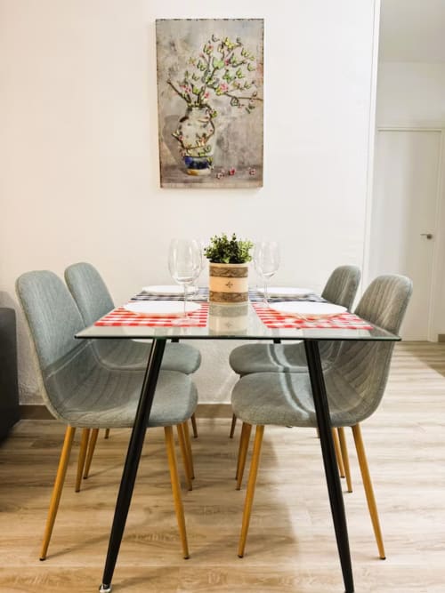 Comedor moderno con sillas grises, manteles a cuadros rojos y planta en maceta en apartamento de Fuengirola
