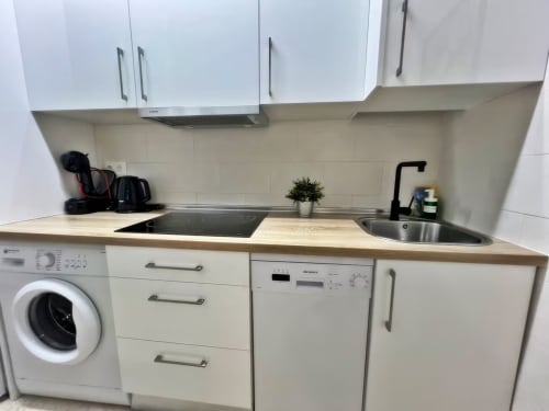 Cocina moderna en apartamento de Fuengirola con armarios blancos, lavavajillas, placa eléctrica, fregadero y lavadora