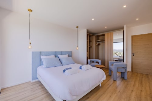 Chambre élégante avec tête de lit bleue, literie blanche, parquet et vue sur mer à Villa Prestige Azur Antilles