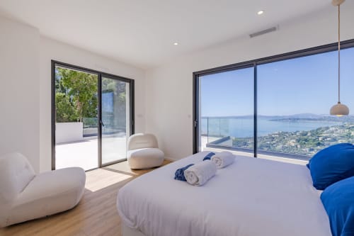 Chambre luxueuse de la villa Perle d'Azur avec vue mer, mobilier moderne et baies panoramiques sur la Méditerranée