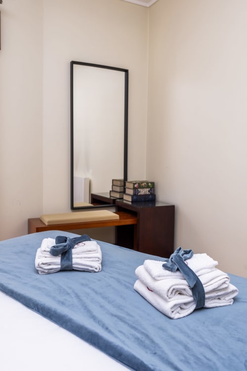 Bedroom with folded towels on blue bed, wooden vanity with mirror at RH Charming Apartments, Barcelos