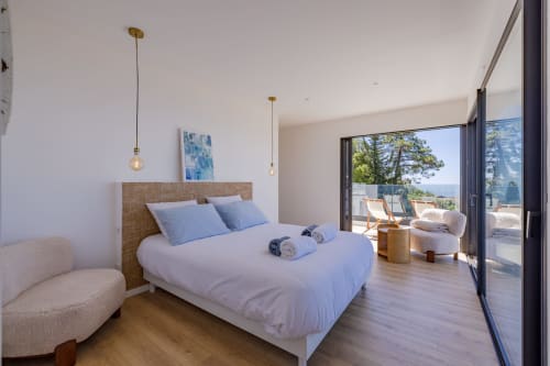 Chambre spacieuse avec terrasse vue mer à la Villa Prestige Azur Antilles, lit moderne, luminaires suspendus et portes ouvertes