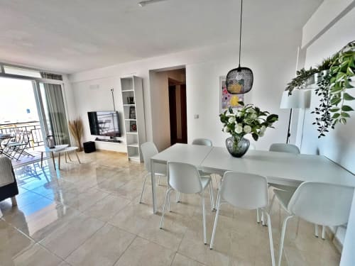 Moderno apartamento frente al mar en Fuengirola con zona de comedor, muebles blancos y vistas a la ciudad desde el balcón