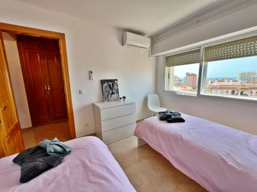Luminoso dormitorio doble en apartamento de playa en Fuengirola con ropa de cama rosa, vistas a la ciudad, aire acondicionado y mobiliario moderno