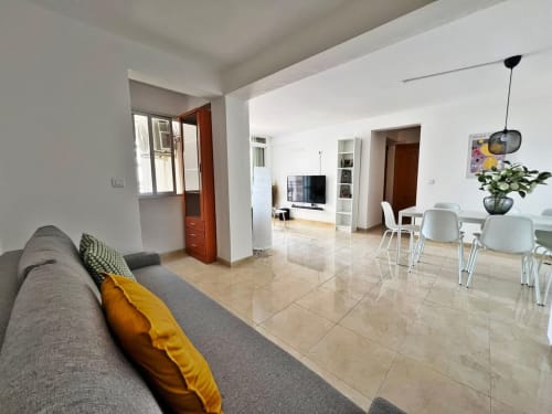 Luminoso apartamento en Fuengirola con sala abierta, sofá gris, comedor y vistas a la ciudad