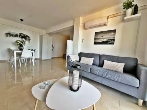 Apartamento moderno en la playa de Fuengirola con sofá gris, mesa redonda blanca, comedor y vistas a la ciudad