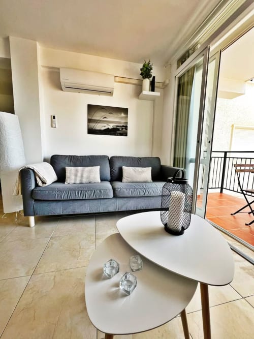 Moderno apartamento de playa en Fuengirola con sofá azul, mesas blancas y balcón con vistas a la ciudad