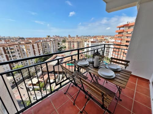 Luminoso balcón de apartamento frente al mar con vistas a la ciudad de Fuengirola, mesa de comedor y vistas al océano