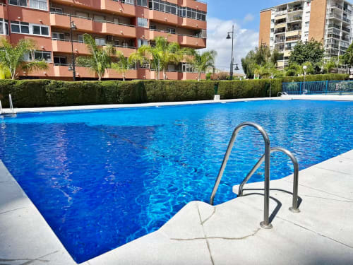 Piscina azul cristalina con barandillas metálicas en apartamento frente al mar en Fuengirola, España
