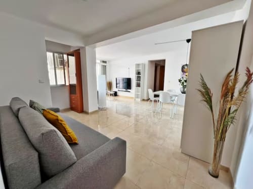 Moderno apartamento de playa en Fuengirola con sala abierta, sofá gris, comedor y vistas a la ciudad