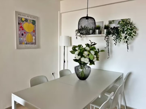 Comedor moderno en apartamento de playa en Fuengirola con mesa blanca, plantas y obra de Hilma af Klint en la pared