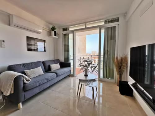 Luminoso apartamento frente al mar en Fuengirola con sofá moderno, vista desde balcón, TV y horizonte urbano