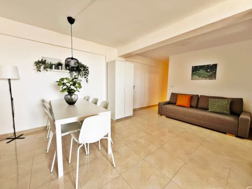 Moderno y luminoso apartamento en Fuengirola con mesa de comedor, sofá marrón y vistas al mar