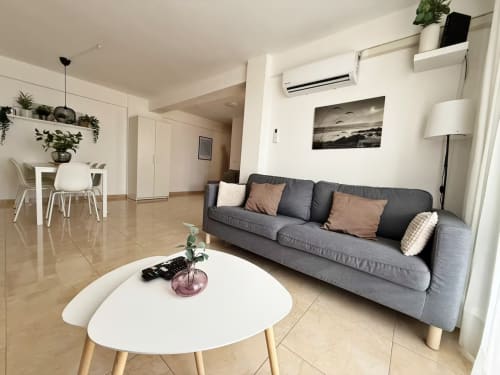 Sala de estar moderna del apartamento de playa en Fuengirola con sofá gris, mesa de café blanca y comedor