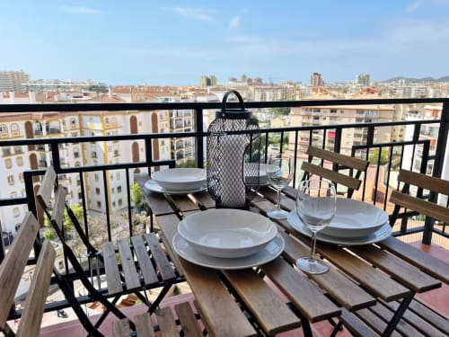 Elegante zona de comedor en azotea del apartamento de Fuengirola con vistas al horizonte urbano y al Mediterráneo