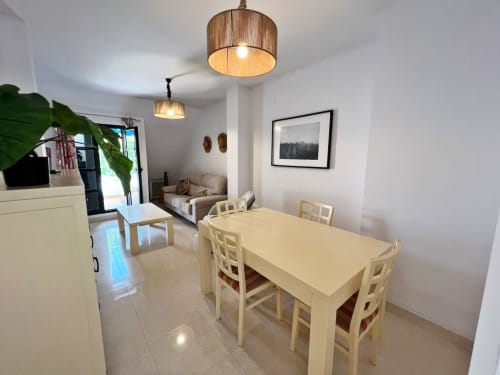 Comedor de apartamento frente al mar en Fuengirola con lámparas colgantes de madera y vistas a la ciudad