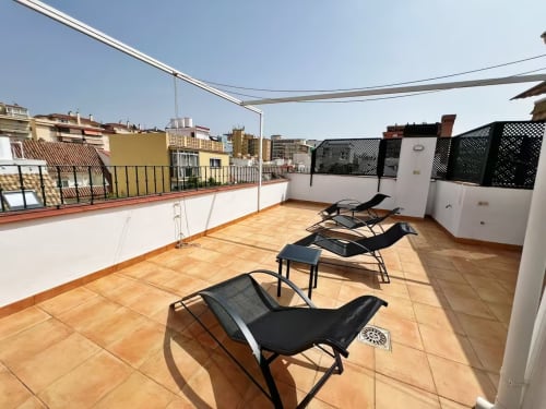 Terraza en la azotea con tumbonas y vistas a la ciudad en apartamento de playa en Fuengirola