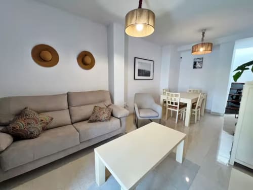Espacioso apartamento moderno en Fuengirola con sofá gris, mesa de comedor y lámparas de techo de madera