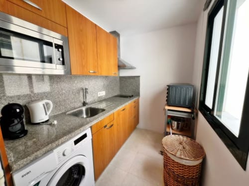 Cocina moderna en apartamento frente al mar, Fuengirola con muebles de madera, electrodomésticos de acero inoxidable, encimera de granito