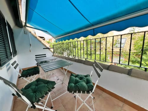 Soleada terraza en ático frente al mar en Fuengirola con toldo retráctil azul, asientos y vistas a la ciudad