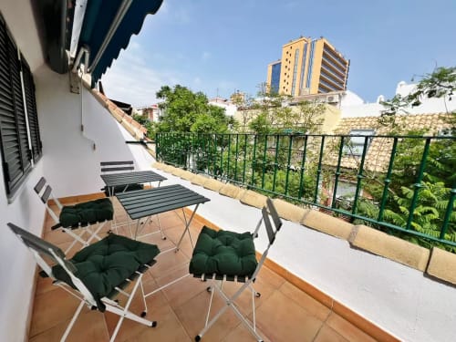 Terraza soleada con tumbonas y cojines verdes con vistas a Fuengirola, apartamento exclusivo en primera línea de playa