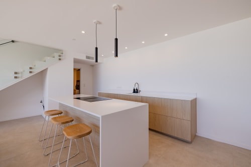 Cuisine moderne de la villa PERLE D'AZUR à Villa Prestige Azur Antilles avec îlot blanc, tabourets en bois et luminaires suspendus