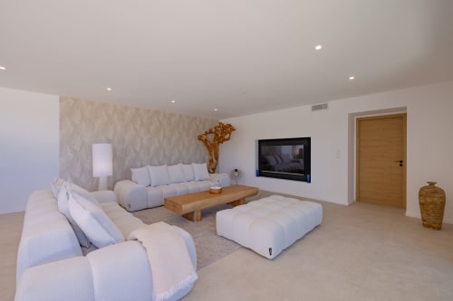 Salon moderne de la villa Perle d'Azur avec sièges confortables, téléviseur mural, accents bois et décor minimaliste